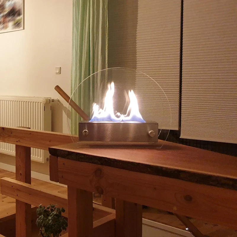 Circular table bioethanol fireplace lit on a wooden shelf in a cozy living room in the evening