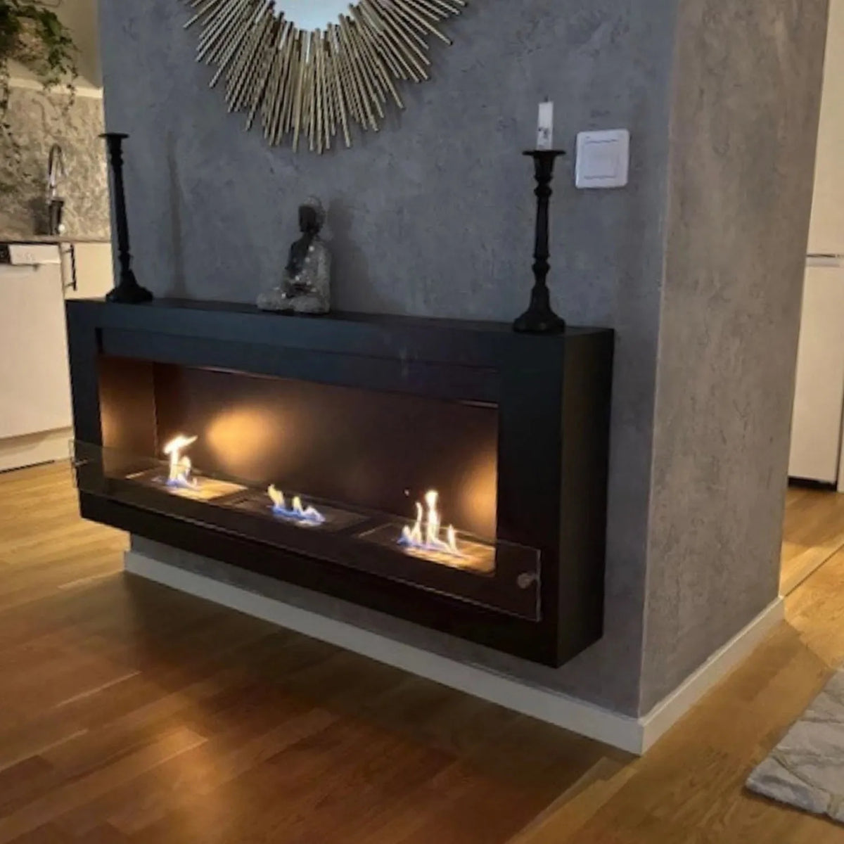 XL black wall-mounted bioethanol fireplace with three lit flames on a grey concrete-look wall, customer photo